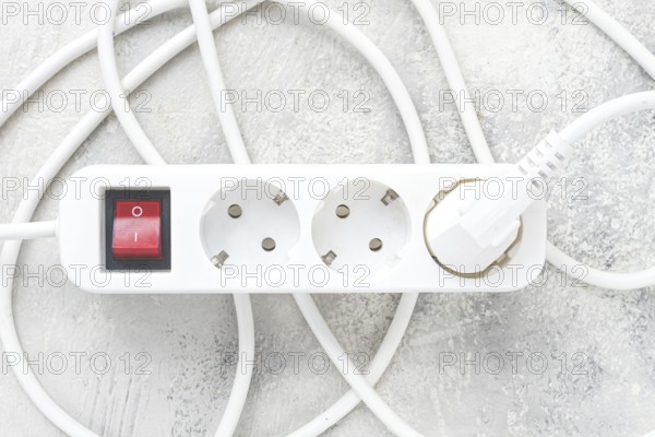 Power strip with multiple sockets and a switch in a cluttered setup on a textured surface during