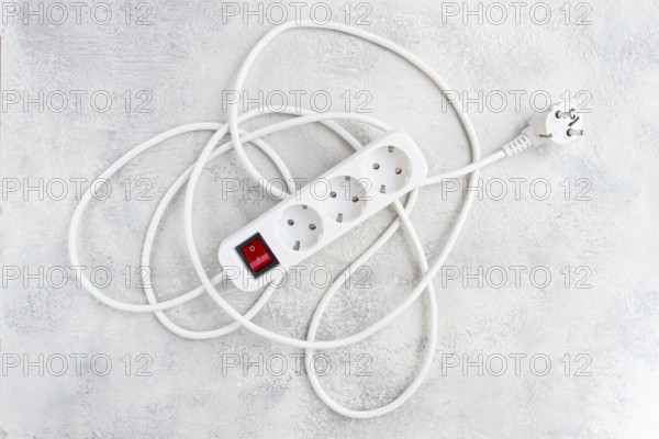 Power strip with multiple sockets and a switch in a cluttered setup on a textured surface during