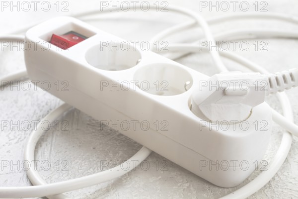 Power strip with multiple sockets and a switch in a cluttered setup on a textured surface during