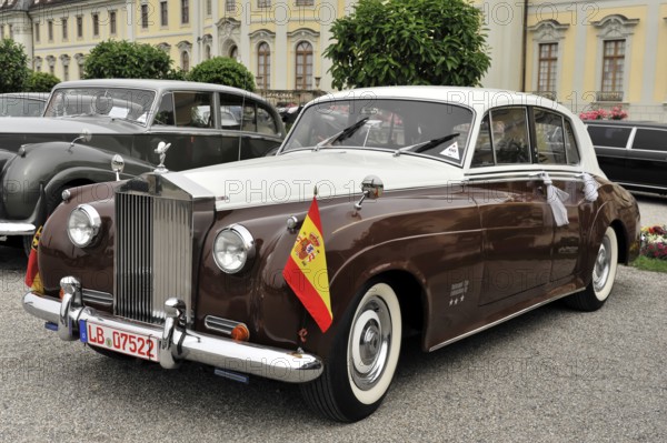 Two-coloured brown and white Rolls-Royce vintage car decorated with flags for a parade, Retro