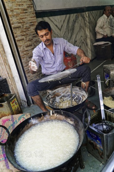 Udaipur, Rajasthan, North India, Asia, Man cooking a traditional dish on the street with pans and