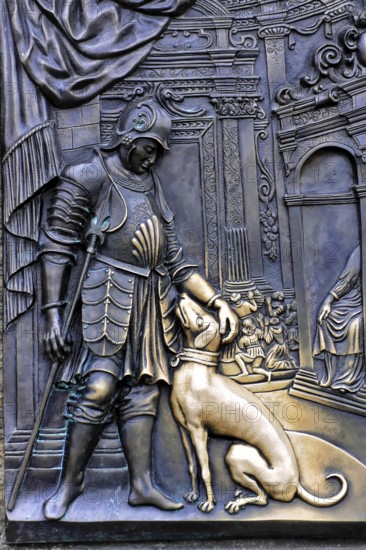 Tourists touch a plaque that is part of the statue of St John of Nepomuk and is supposed to bring
