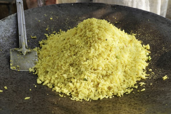 Kota, Rajasthan, North India, Asia, A large pile of poha in an iron pan with a spatula next to it,