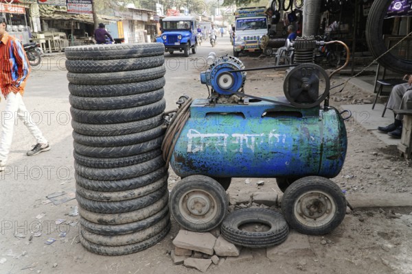 Kota, Rajasthan, North India, Asia, A pile of tyres next to a blue compressor in a dusty workshop
