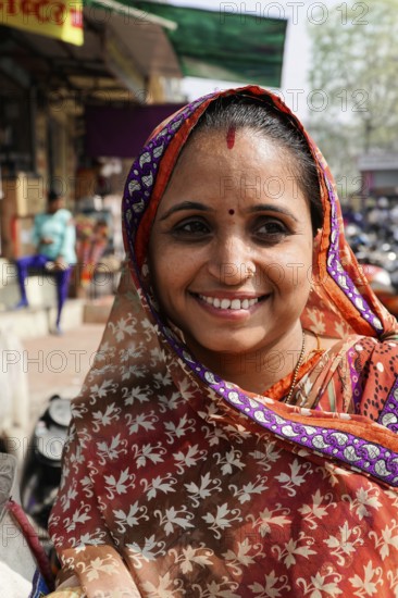 Kota, Rajasthan, North India, Asia, Smiling woman in traditional Indian sari in front of a busy