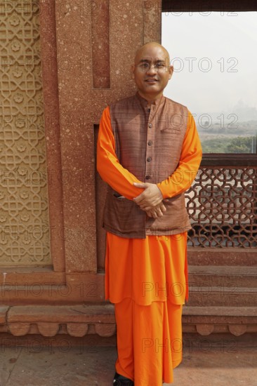 Agra, Uttar Pradesh, India, Asia, A monk in orange-coloured clothes stands in front of a historical