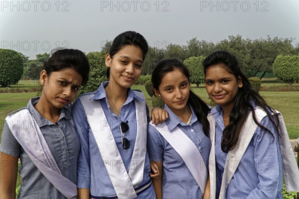 Four girls in uniform standing close together and smiling in a garden, Agra, Jodhpur, Rajasthan,