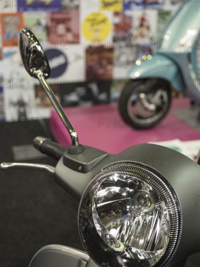 Retro scooter mirror in front of a blurred background with posters and another scooter, dortmund,
