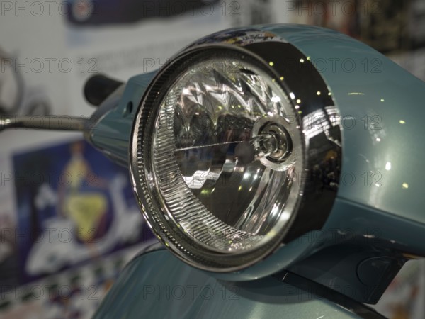 Close-up view of a retro scooter headlight with shiny chrome and a blue housing, dortmund,