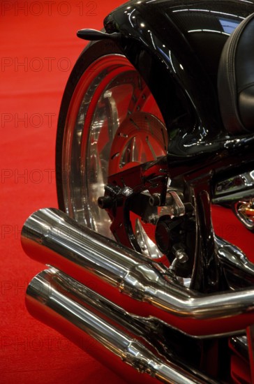 Exhaust system of a black motorbike against a red background, emphasising elegant lines, dortmund,
