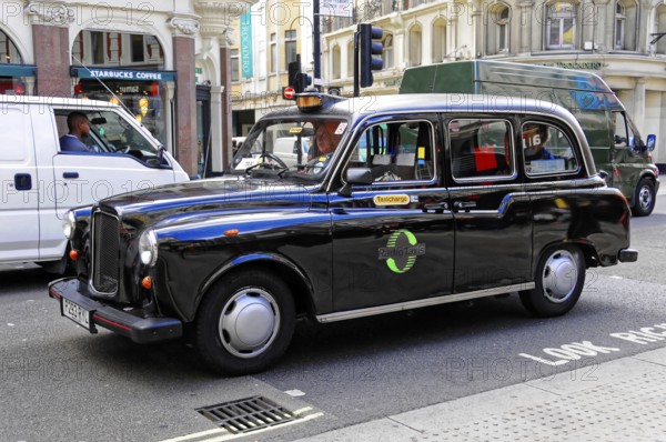 Black taxi driving on a busy London street in daylight, London, London region, England, United