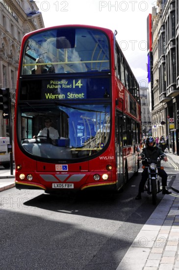 Red double-decker bus travelling along a busy London street, London, London region, England, United