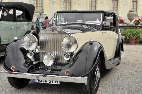 Black and cream-coloured classic car with striking front grille and round headlights, Retro