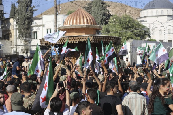 Thousands of Syrians march in Idlib carrying the Syrian revolutionary flag during a protest against