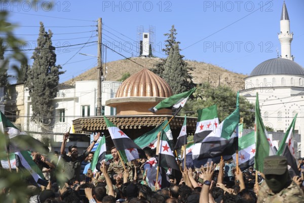 Thousands of Syrians march in Idlib carrying the Syrian revolutionary flag during a protest against