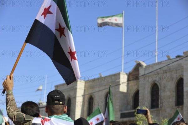 Thousands of Syrians march in Idlib carrying the Syrian revolutionary flag during a protest against