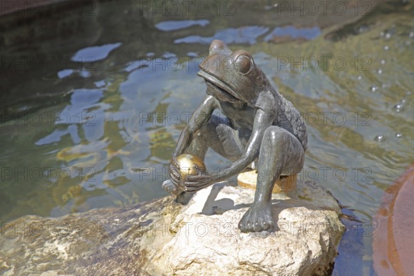 Frog King with golden ball by the water, sculpture, fairytale figure, fairytale fountain, market