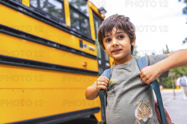 Elementary school student wearing a backpack, waiting for the bus on a bright, sunny day, excitedly