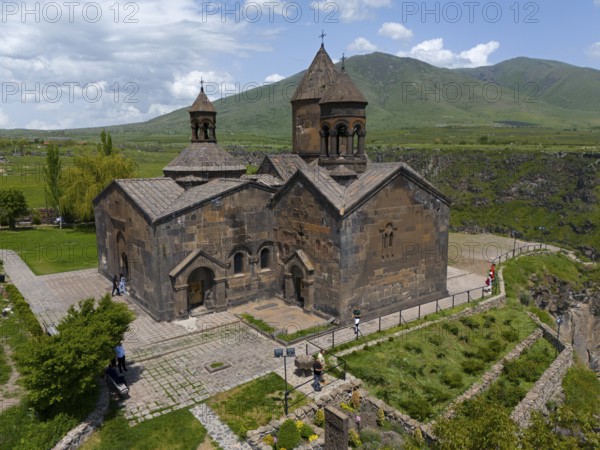 Stone church with natural backdrop and mountain view on paved terrain, aerial view, Saghmosavank