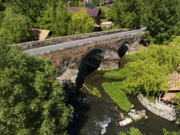 Aerial view of an old stone bridge over a winding river in green nature, aerial view, bridge from