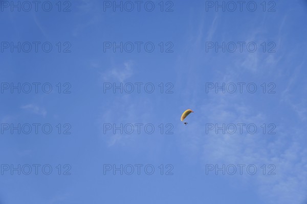 Paragliding on a sunny day with cirrus clouds, enjoying freedom and adventure in ronda, malaga,
