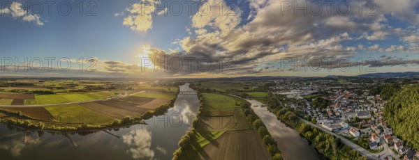 The sunset bathes the river landscape of the Danube in a warm light. A few fields and meadows