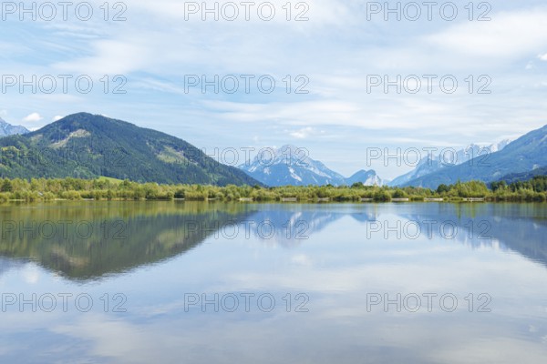 Panoramic lake reflects the surrounding mountains and the slightly cloudy sky, Admont, Styria,