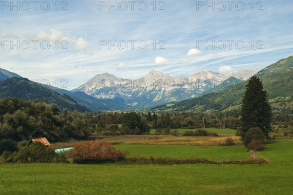 Wide meadows stretch out in front of an alpine mountain range, Haller Mauern, under a clear sky,