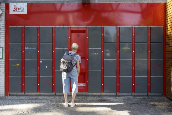 Woman standing in front of locker system, lockers, railway station, Bamberg, Upper Franconia,