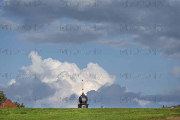 Tower of a chapel behind a meadow hill, cloudy sky, Köttweinsdorf, Upper Franconia, Bavaria,