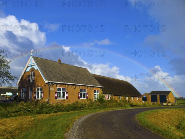 A picturesque farm in the countryside with a rainbow over the blue sky, former monastery, farm with