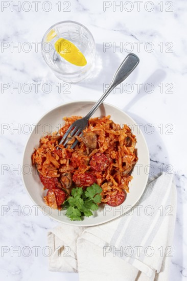 Bigos, Polish dish bigos, on a marble table, stewed meat with cabbage, chorizo sausages, mushrooms,