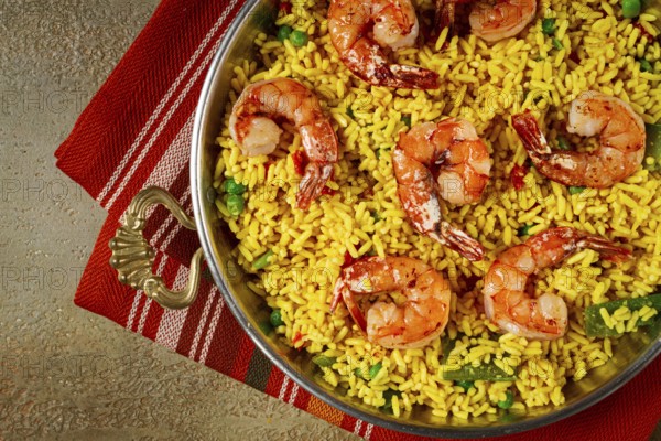 Rice with saffron and shrimp, in a frying pan, paella with shrimp, top view, homemade, no people