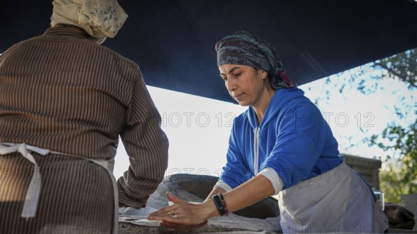 A Turkish woman bakes traditional bread on a clay tandoor oven in a rural village, Hatay, Hatay,