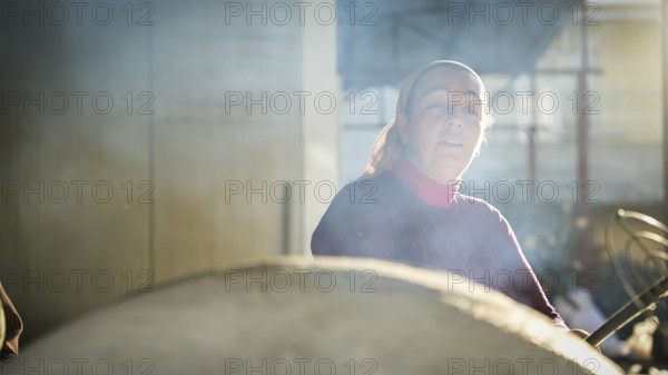 A Turkish woman bakes traditional bread on a clay tandoor oven in a rural village, Hatay, Hatay,