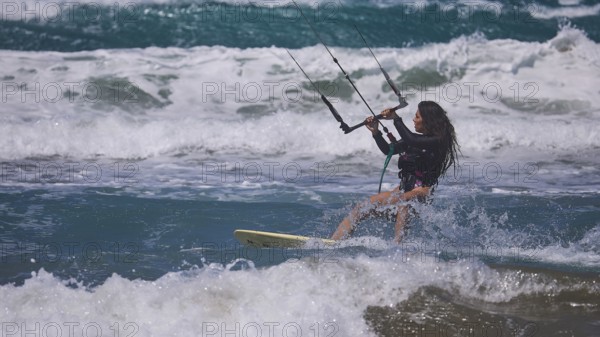Woman kitesurfing energetically over waves in sunny sea environment, Prasonisi, beach, surf,
