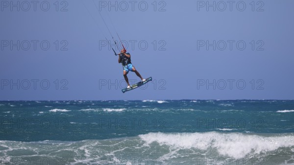 Kitesurfer jumping high over waves under a clear blue sky, Prasonisi, beach, surf, windsurfer, kite