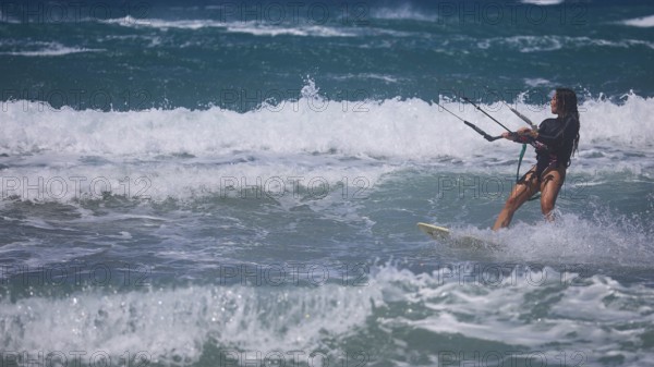 Kitesurfer gliding through moving waves in the ocean under blue sky, Prasonisi, beach, surf,