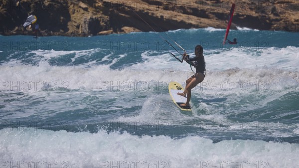 Kitesurfer skilfully navigates the waves off the rocky coast, Prasonisi, beach, surf, windsurfer,