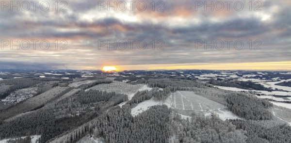 Aerial view of the sunset with a view over the snowy winter landscape from Winterberg to the