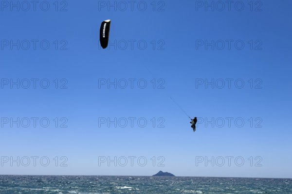 Kitesurfer kite surfer makes big high giant jump with kite kite sail over sea surface,