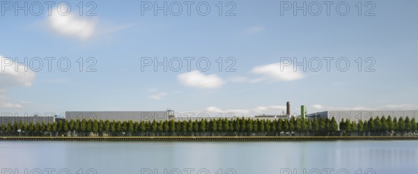 View across the Mittelland Canal to an industrial building with trees growing in front of it, long