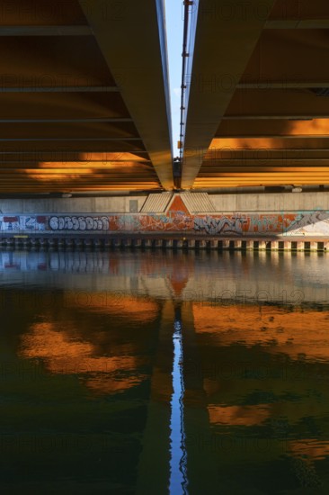 View across the Mittelland Canal to the underside and the graffiti-painted abutment of a bridge on