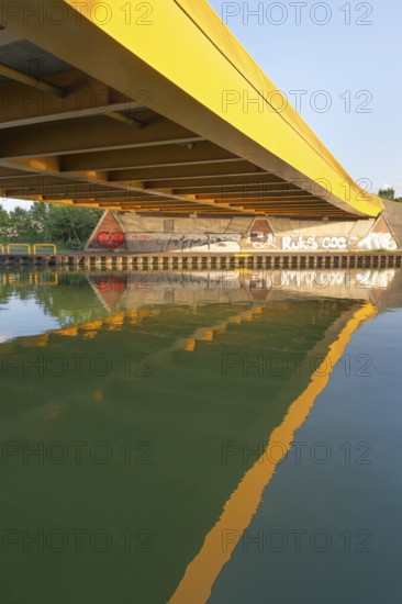View across the Mittelland Canal to the underside and the graffiti-painted abutment of a bridge on