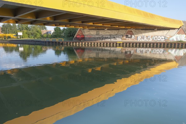 View across the Mittelland Canal to the underside and the graffiti-painted abutment of a bridge on