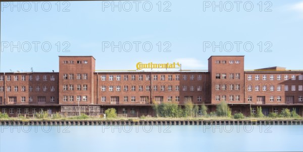 View across the Mittelland Canal to an industrial building with trees growing in front of it, long