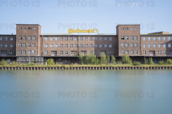 View across the Mittelland Canal to an industrial building with trees growing in front of it, long