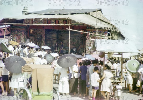 Audience watching Chinese theatre performance at the old market, Johor Bahru, Johor, Malaya,