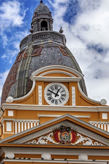 Architecturally richly decorated tower with clock and coat of arms under a cloudy sky, The