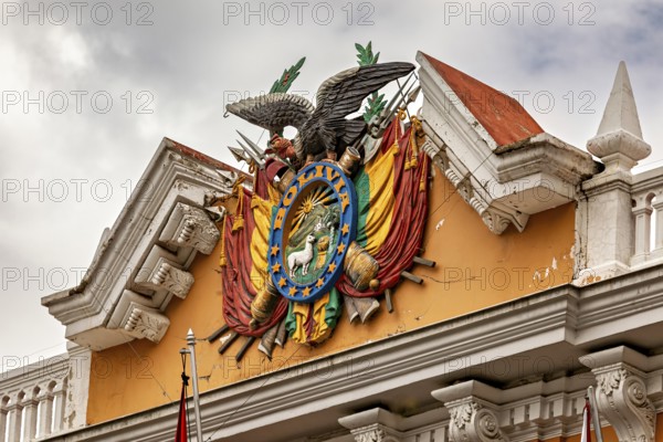 Detailed coat of arms with eagle on a historic building under a cloudy sky, The Presidential Palace